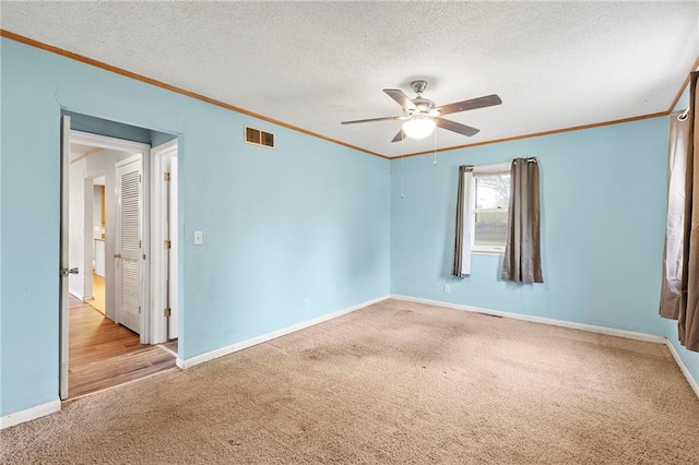 unfurnished room featuring ornamental molding, ceiling fan, carpet flooring, visible vents, and a textured ceiling