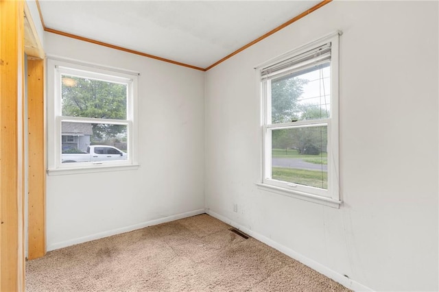 empty room with visible vents, ornamental molding, a healthy amount of sunlight, and carpet flooring