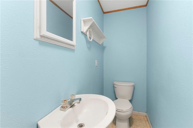 half bathroom with toilet, tile patterned flooring, a sink, and ornamental molding