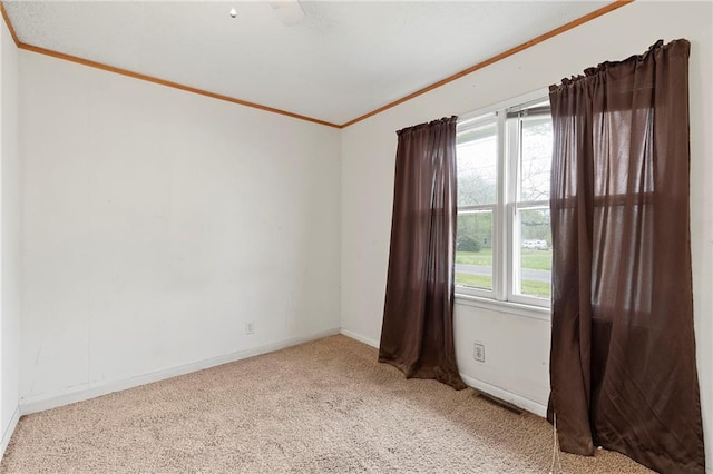 spare room with ornamental molding, carpet flooring, a wealth of natural light, and visible vents