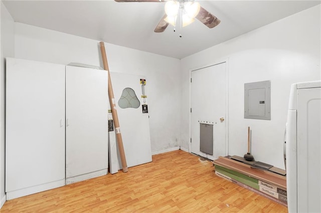 interior space with washer / dryer, a ceiling fan, electric panel, and light wood-style flooring