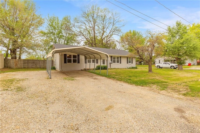 view of front facade featuring a front lawn, driveway, a detached carport, and fence