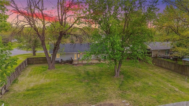 yard at dusk featuring a fenced backyard