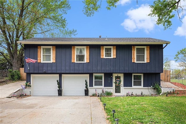 view of front of home featuring board and batten siding, fence, driveway, a front lawn, and an attached garage