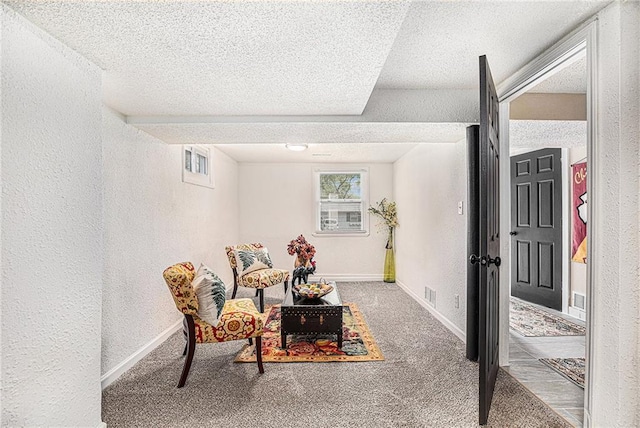 living area with carpet flooring, visible vents, a textured ceiling, and a textured wall