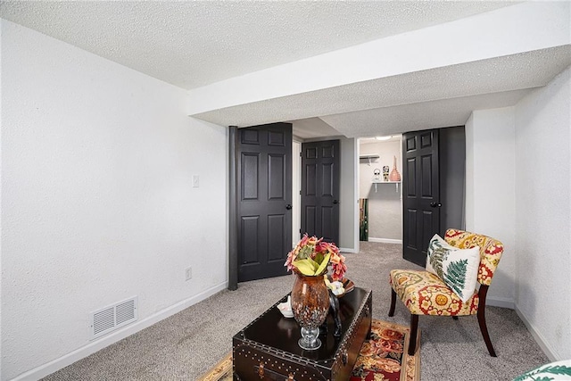 sitting room with baseboards, visible vents, carpet floors, and a textured ceiling