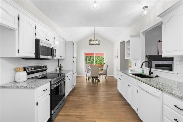 709 SW Graystone Dr, Grain Valley, MO 64029 - kitchen with stainless steel appliances, a chandelier, wood finished floors, lofted ceiling, and white cabinets