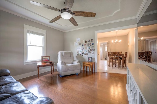 living area with crown molding, baseboards, ceiling fan with notable chandelier, and wood finished floors