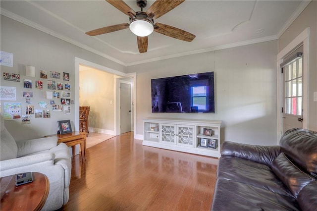 living area with baseboards, ceiling fan, ornamental molding, and wood finished floors