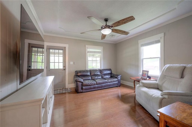 living area featuring ceiling fan, visible vents, ornamental molding, and light wood-style floors
