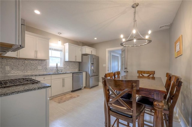 kitchen with decorative backsplash, visible vents, appliances with stainless steel finishes, a sink, and a chandelier