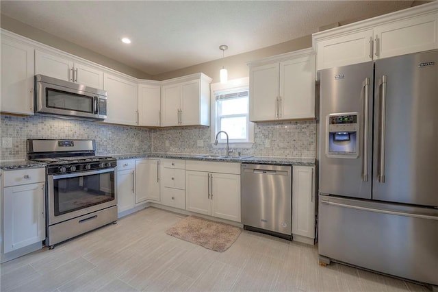 kitchen with a sink, dark stone countertops, tasteful backsplash, and stainless steel appliances