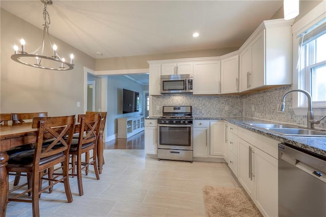 kitchen with decorative backsplash, a sink, white cabinets, a notable chandelier, and stainless steel appliances