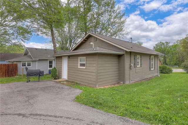 rear view of property featuring a lawn and fence