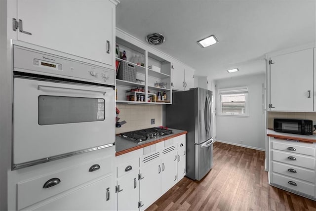 kitchen with backsplash, stainless steel appliances, white cabinetry, and dark wood-type flooring