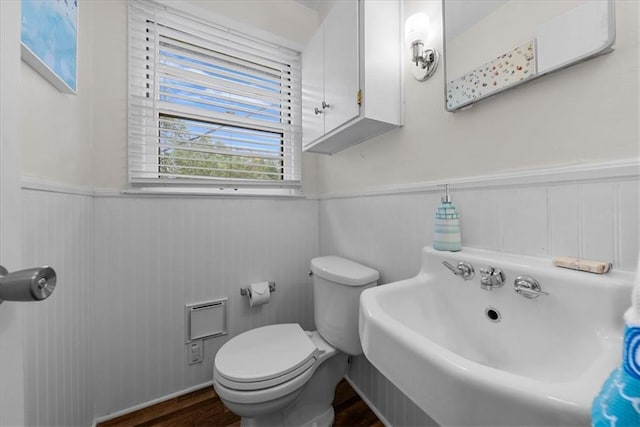 bathroom featuring a sink, a wainscoted wall, toilet, and wood finished floors