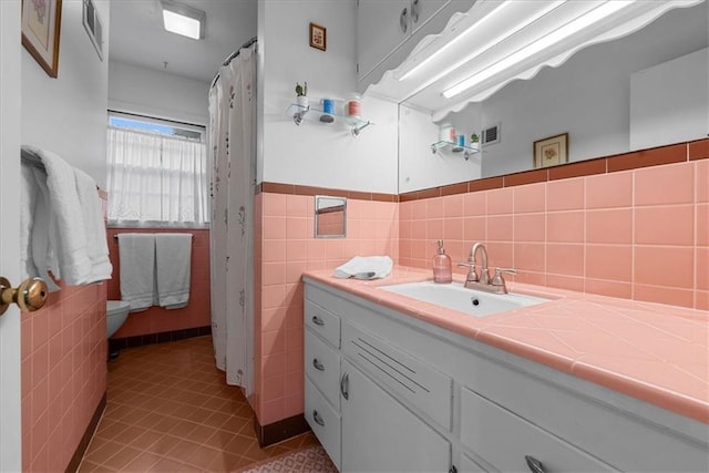 full bathroom with visible vents, tile walls, wainscoting, vanity, and toilet