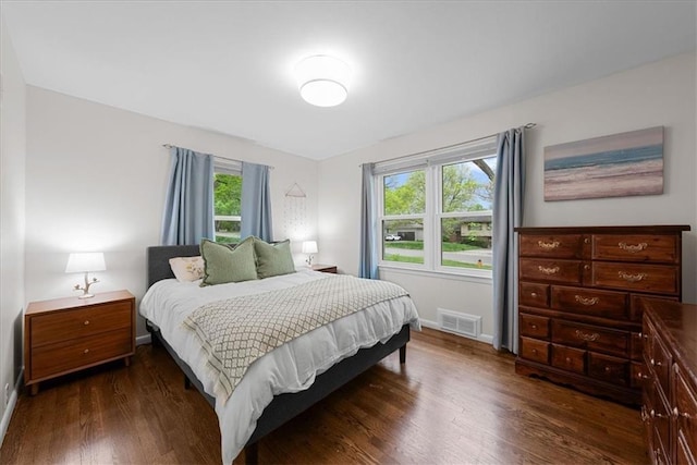 bedroom with baseboards, dark wood finished floors, and visible vents