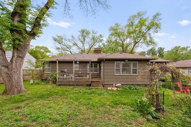 rear view of house with fence, a chimney, a lawn, and a deck