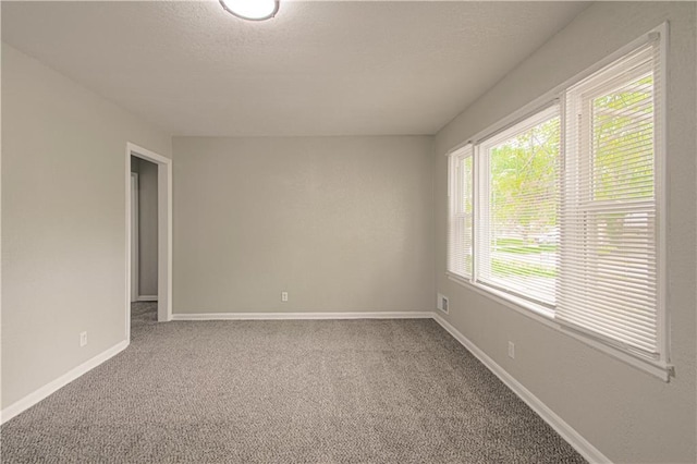 carpeted spare room with baseboards and a textured ceiling