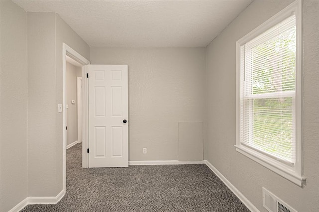 carpeted spare room with a textured ceiling, visible vents, and baseboards