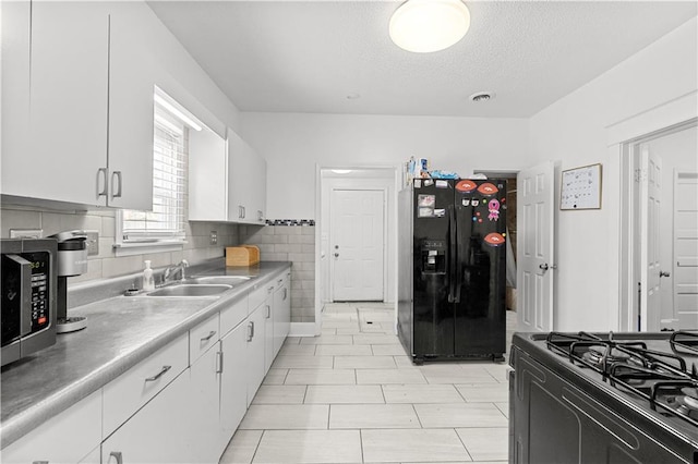 69 N Valley St, Kansas City, KS 66102 - kitchen featuring black appliances, a sink, white cabinetry, a textured ceiling, and light countertops