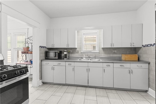 69 N Valley St, Kansas City, KS 66102 - kitchen with appliances with stainless steel finishes, a sink, white cabinetry, decorative backsplash, and light countertops