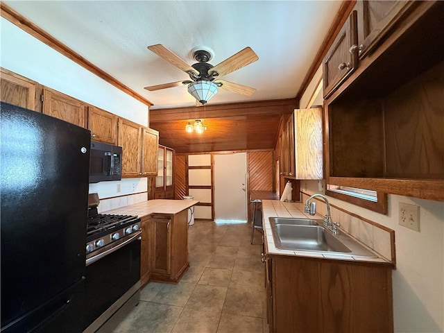 1450 Central St, Leavenworth, KS 66048 - kitchen featuring wooden walls, ceiling fan, a sink, brown cabinetry, and black appliances