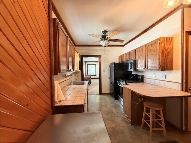 1450 Central St, Leavenworth, KS 66048 - kitchen featuring a ceiling fan, tile countertops, appliances with stainless steel finishes, brown cabinets, and a sink