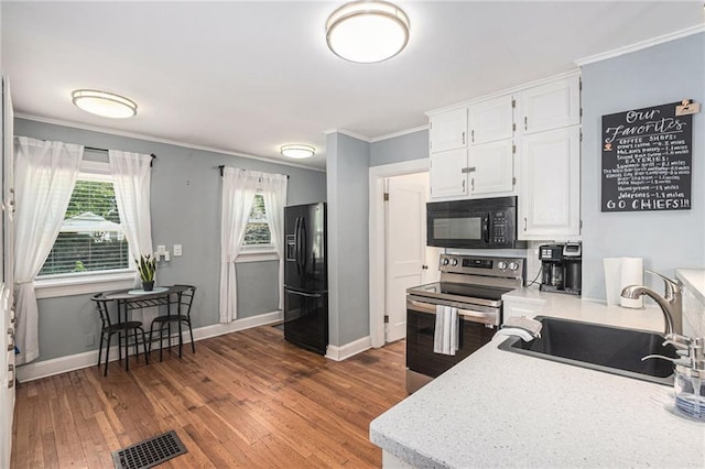 kitchen with a sink, crown molding, black appliances, white cabinets, and wood finished floors