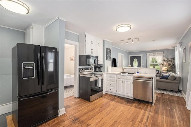 kitchen with white cabinets, black appliances, a peninsula, and ornamental molding