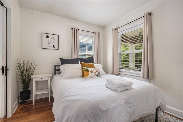 bedroom with wood finished floors, crown molding, and baseboards