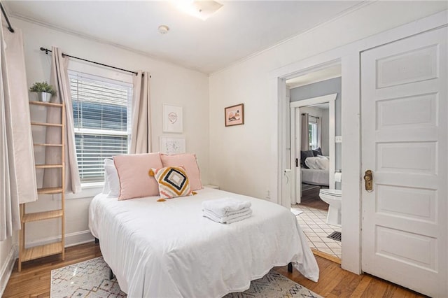 bedroom with baseboards, wood finished floors, and crown molding