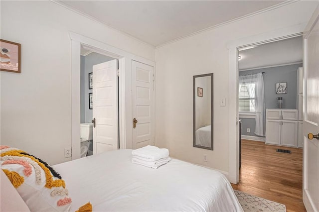 bedroom featuring visible vents, light wood-style floors, ornamental molding, and baseboards