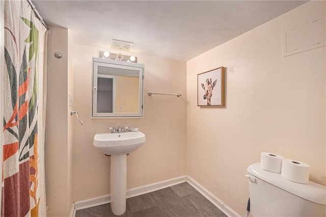 bathroom featuring toilet, visible vents, baseboards, wood finished floors, and a shower with shower curtain