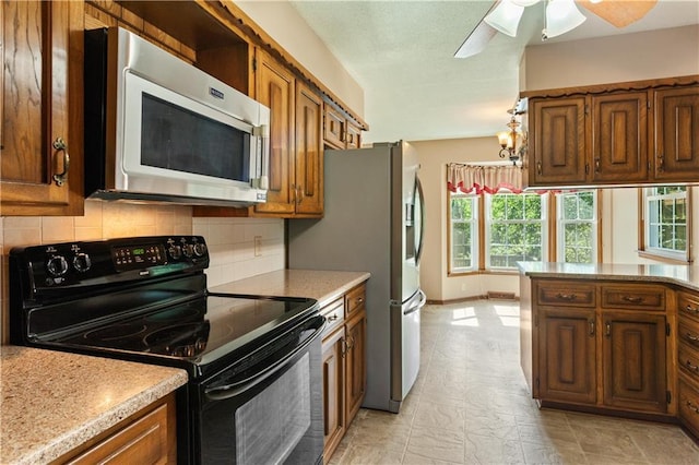 3311 S Crane St, Independence, MO 64055 - kitchen featuring appliances with stainless steel finishes, brown cabinetry, healthy amount of natural light, and backsplash