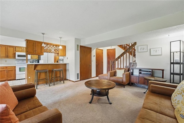 living area with light colored carpet, a textured ceiling, and stairs