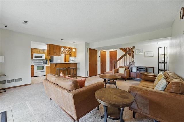 living room with stairway, light colored carpet, light tile patterned floors, a textured ceiling, and baseboards
