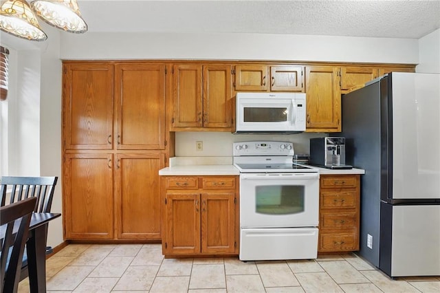 kitchen with white appliances, brown cabinets, light countertops, and light tile patterned flooring