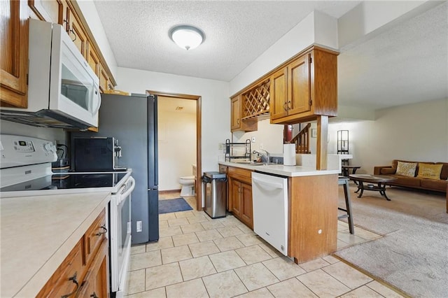 kitchen featuring white appliances, open floor plan, brown cabinets, light countertops, and a textured ceiling