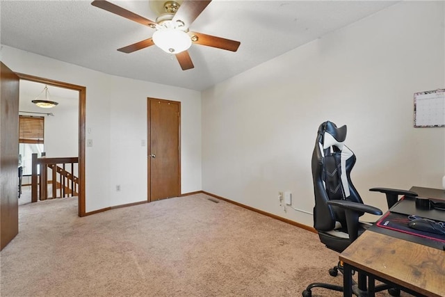 carpeted home office with ceiling fan and baseboards