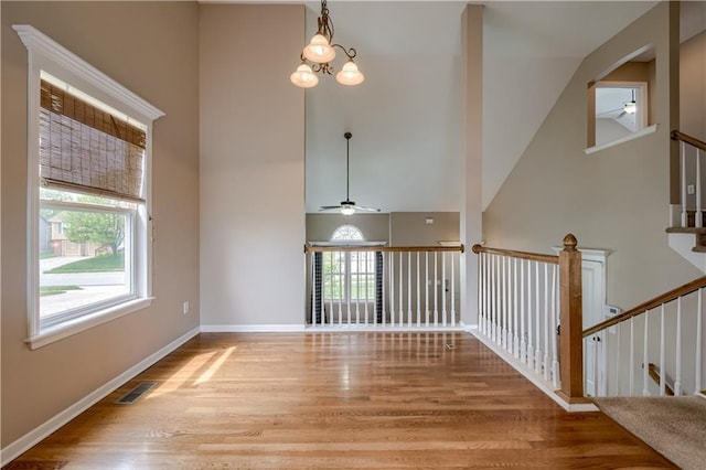 spare room with visible vents, wood finished floors, baseboards, high vaulted ceiling, and a ceiling fan