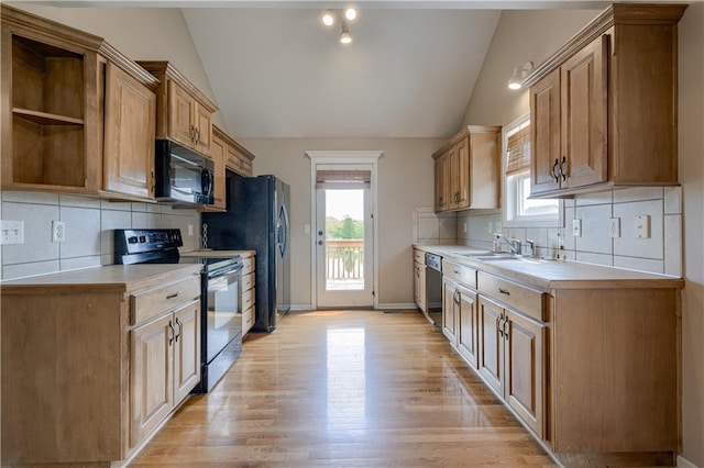kitchen featuring light countertops, vaulted ceiling, decorative backsplash, and black appliances