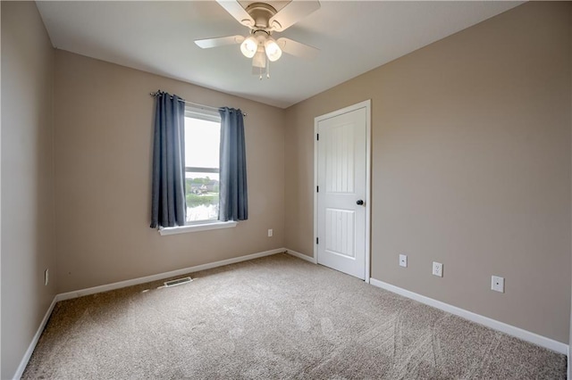 carpeted empty room with baseboards, ceiling fan, and visible vents