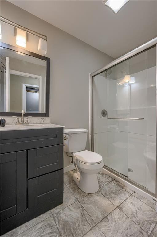 bathroom featuring vanity, a shower stall, and toilet
