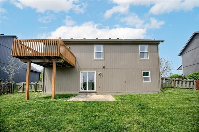 rear view of house with a yard, a deck, and a fenced backyard