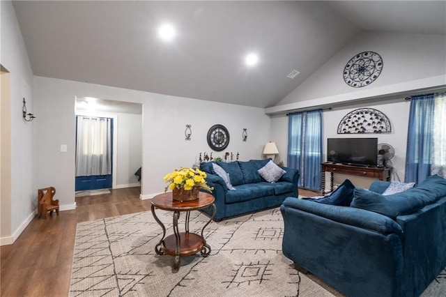 living area featuring wood finished floors, plenty of natural light, high vaulted ceiling, and baseboards