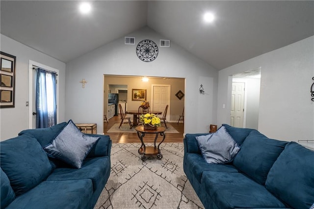 living area featuring visible vents, high vaulted ceiling, and light wood finished floors