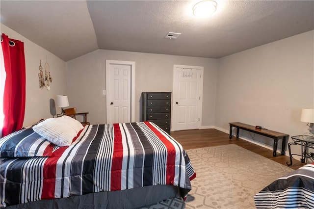 bedroom with visible vents, vaulted ceiling, and wood finished floors