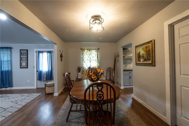dining area featuring dark wood-style floors, baseboards, and a textured ceiling
